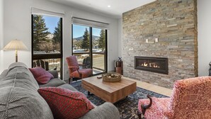 A living room with a stone fireplace, large windows, and a cozy seating area. - Charming 3BR Mountain Retreat in Silverthorne, CO (Silverthorne)
