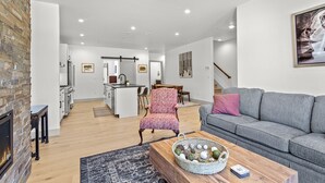 A modern living room with a grey sofa, a coffee table with decorative items, a patterned armchair, and a fireplace. - Charming 3BR Mountain Retreat in Silverthorne, CO (Silverthorne)