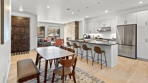 A modern kitchen with a central island, stainless steel appliances, and a dining area with wooden furniture. - Charming 3BR Mountain Retreat in Silverthorne, CO (Silverthorne)
