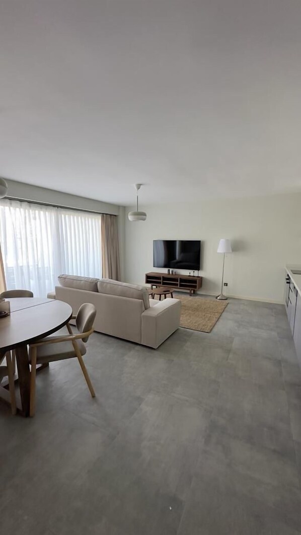 A modern living room with a sofa, a TV, and a dining area with a table and chairs. - Bono Premium Collection (Marmaris)