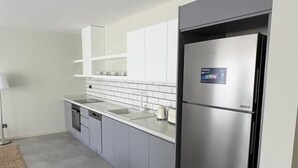 A modern kitchen with grey cabinets, a stainless steel refrigerator, and a white countertop. - Bono Premium Collection (Marmaris)