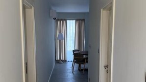 A hallway with a ceiling light, a dining area with a table and chairs, and a window with curtains. - Bono Premium Collection (Marmaris)