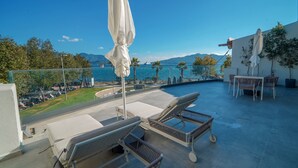 A rooftop terrace with lounge chairs, a table, and a view of the sea and mountains. - Bono Premium Collection (Marmaris)