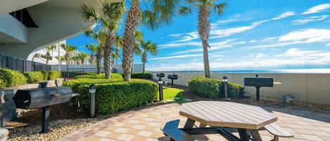 Enjoy a meal at the picnic table surrounded by palm trees and enjoy the beach view while grilling in this outdoor space