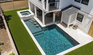 Une piscine rectangulaire bordée de pierres, entourée d’une pelouse bien entretenue.