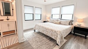 Een slaapkamer met een bed, nachtkastjes, een plafondventilator en een raam met jaloezieën.