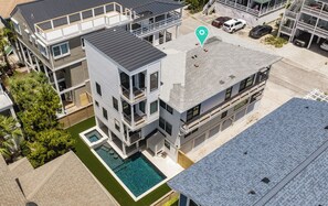 Un immeuble moderne à plusieurs étages, doté d’une piscine sur le toit, de balcons et d’un garage.