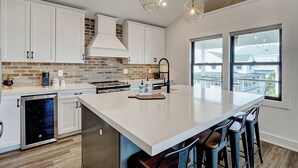 Een moderne keuken met witte kasten, een groot eiland en een backsplash van baksteen.