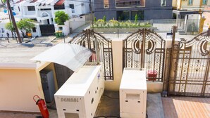 A gated area with a white building, a fire extinguisher, and a metal gate. - Annes luxury suites  (Lagos)