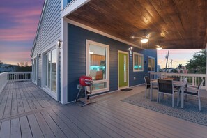 A covered deck with a barbecue grill, outdoor seating, and a view of the neighborhood. - Canal Front- Easy Walk to Beach- 2BR Flip Flops Forever (Fort Myers Beach)