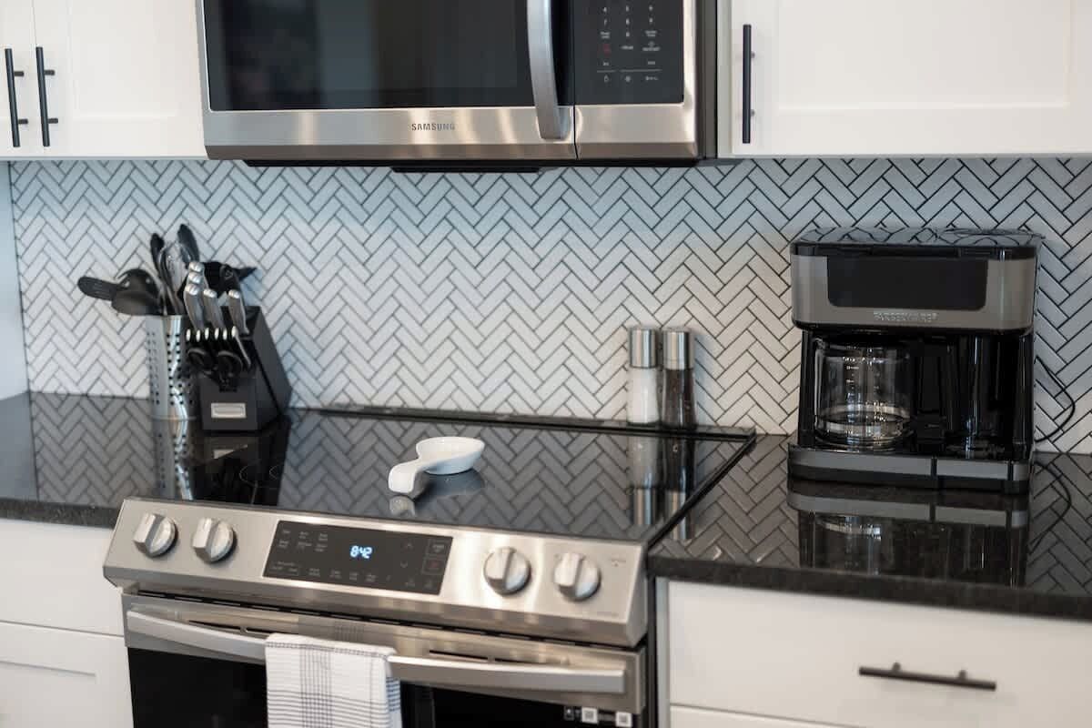 A kitchen with a stainless steel microwave, a coffee maker, and a stove.