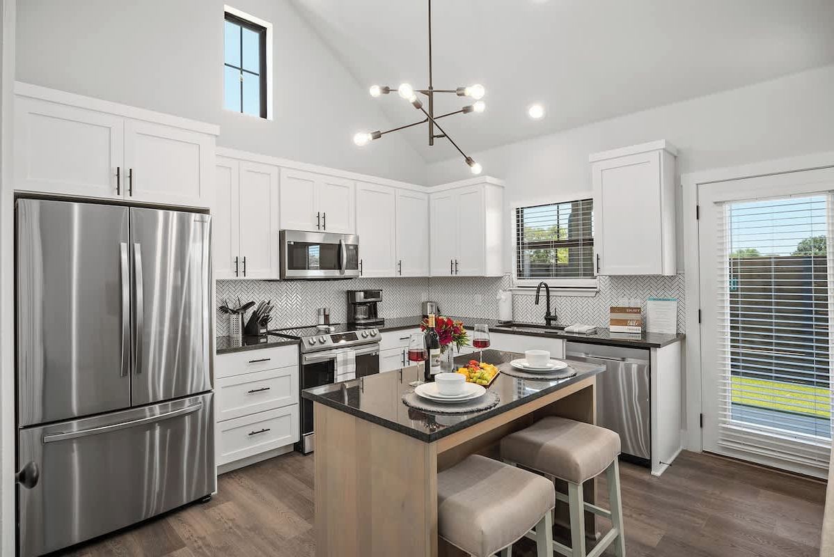 A modern kitchen with white cabinetry, stainless steel appliances, and a central island with seating.