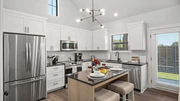 A modern kitchen with white cabinetry, stainless steel appliances, and a central island with seating.