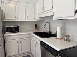 A modern kitchen with white cabinetry, a black microwave, a stainless steel sink, and a dishwasher. - Quiet mountain retreat convenient to hiking and Asheville (Weaverville)