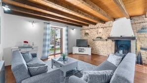A modern living room with a fireplace, wooden beams, and a stone wall. - Enchanting Villa Marijanin Vrt with swimming pool (Tinjan)