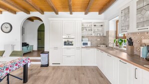 A modern kitchen with white cabinetry, a wooden ceiling, and a view into the dining area. - Enchanting Villa Marijanin Vrt with swimming pool (Tinjan)