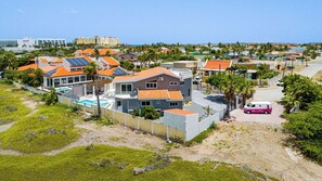 Un quartier résidentiel avec des maisons, une piscine et un véhicule rose.