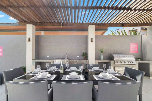 An outdoor dining area with a grill and a table set for a meal.