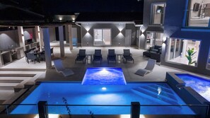 Un espace piscine extérieur moderne, doté de chaises longues et d’un jacuzzi.