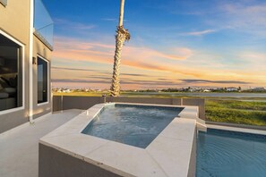Un espace piscine extérieur moderne offrant une vue dégagée sur un paysage lointain et agrémenté d’un grand palmier.