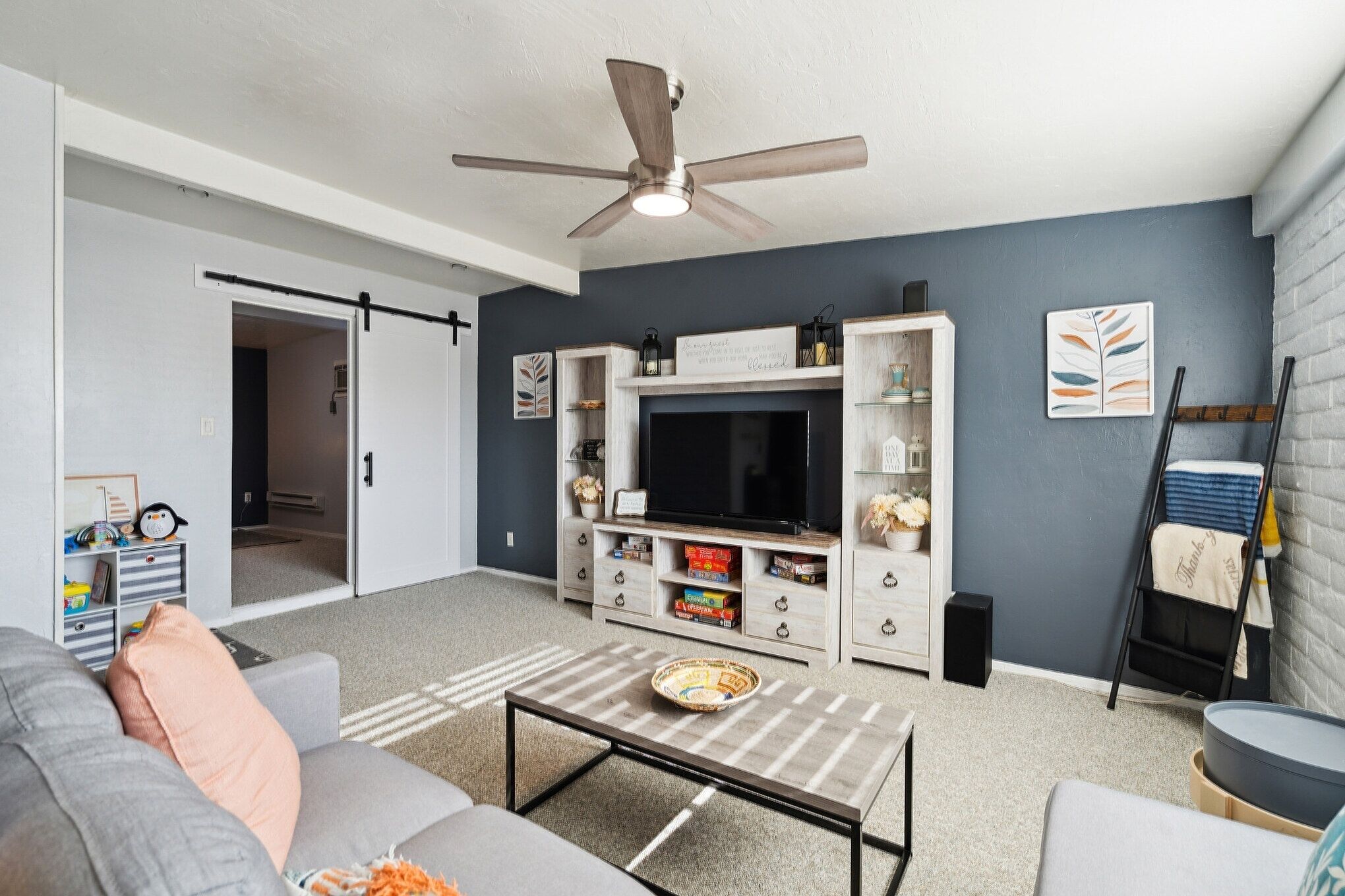 A living room with a grey sofa, a coffee table, a TV, and a bookshelf.