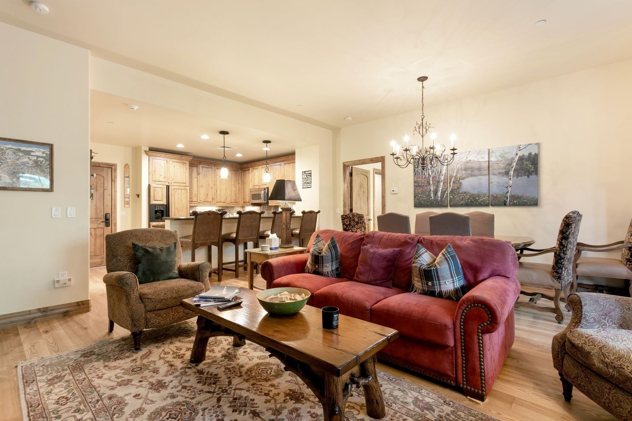Ein geräumiges Wohnzimmer mit einem roten Sofa, Holzsesseln, einem Couchtisch und einer Chandelier.
