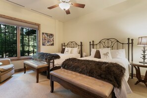 A bedroom with two beds, a bench, a chair, and a window with a view of trees. - B107 Beaver Creek Landing 3 Bedroom Condo by RedAwning (Avon)