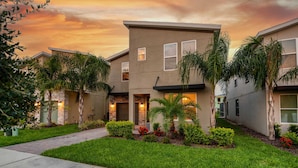A modern two-story house with a well-maintained lawn, a pathway leading to the entrance, and a sunset sky. - 6BR getaway w/ pool, hot tub & game room (Four Corners)