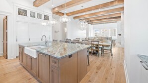 A spacious kitchen with a large island, wooden beams, and pendant lighting.