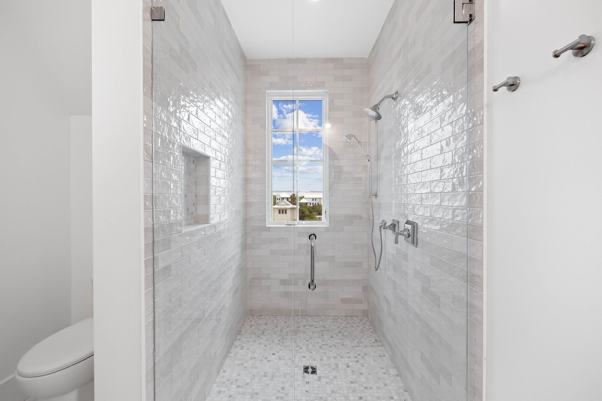Une salle de bain moderne avec une douche à l’italienne, une fenêtre et des toilettes.
