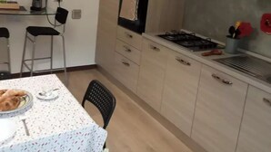 Cocina compacta con estufa a gas, horno y un pequeño comedor con mesa y sillas.