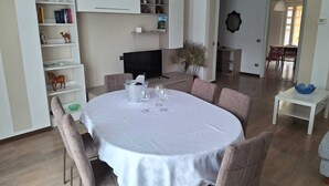 Un comedor con una mesa redonda, sillas, un televisor y una estantería.