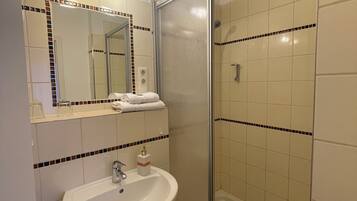 Een badkamer met een wastafel, spiegel en douche.