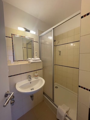 Une salle de bain avec un lavabo, un miroir et une douche.