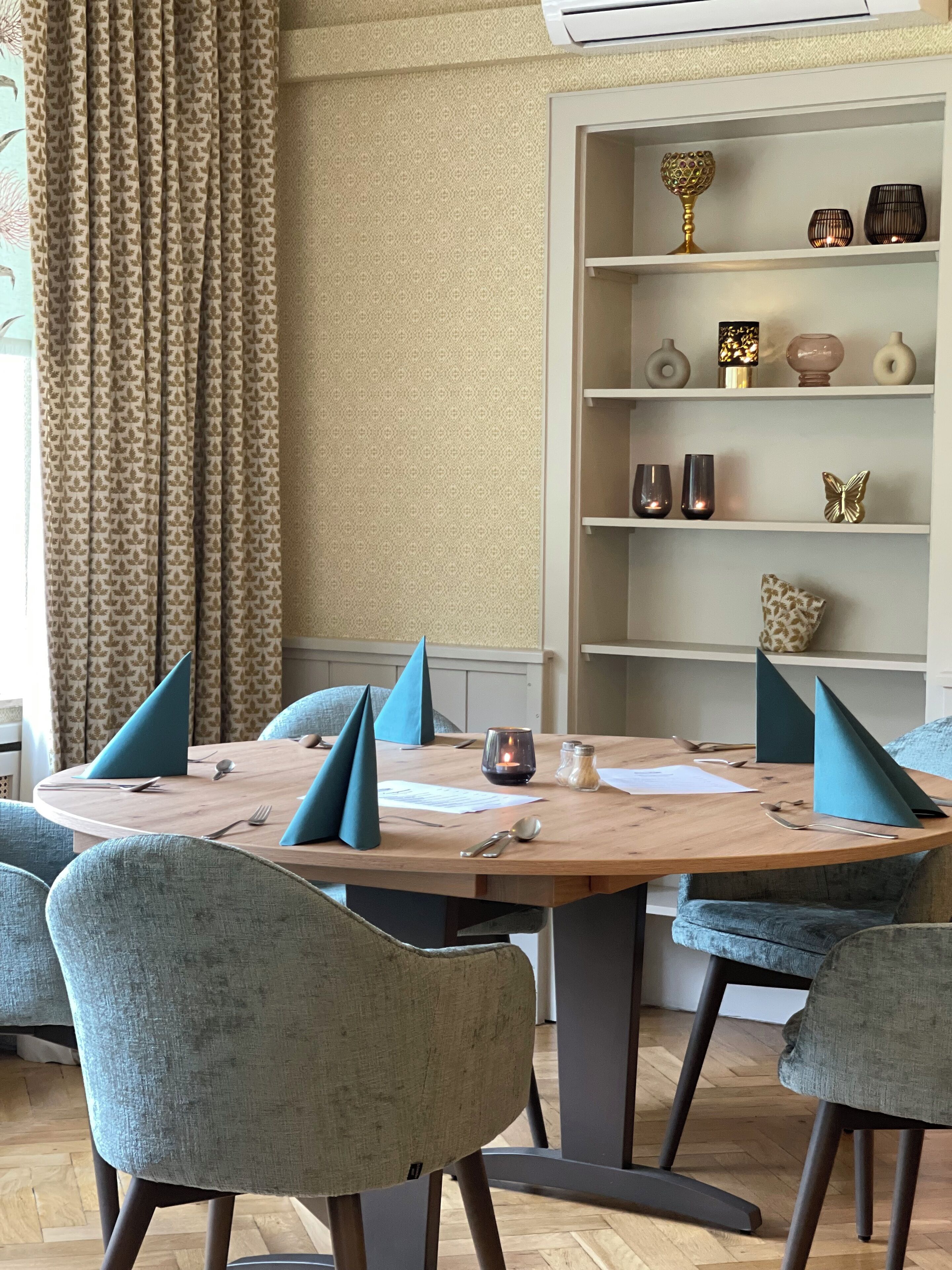 Un coin repas avec une table ronde, des serviettes bleues et des chaises grises.