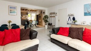 Ein geräumiger Wohnbereich mit zwei Sofas, einem Esstisch und einer Küche im Hintergrund.