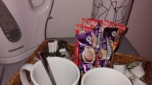 Un plateau en osier contenant deux tasses blanches, une machine à café Daewoo et un paquet de café.