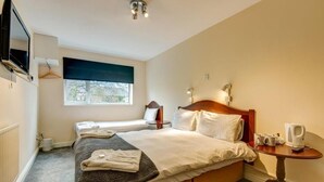 Une chambre d’hôtel avec un lit, une table de chevet, une télévision et une fenêtre.