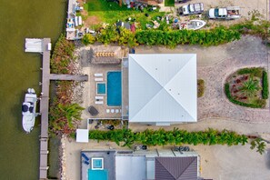 An aerial view of a property with a swimming pool, a dock with boats, and a large building.