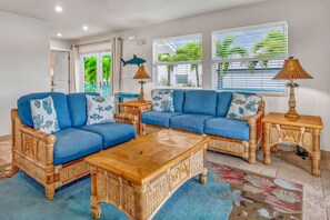 A living room with two blue sofas, a wooden coffee table, and a wooden side table with a lamp.
