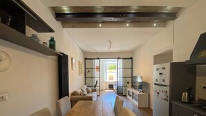 A modern kitchen with a wooden dining table, built-in appliances, and a sliding glass door leading to a bright room.