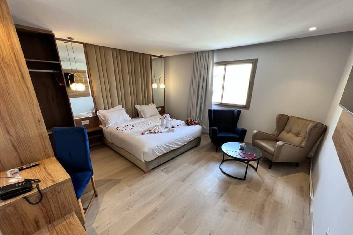 A hotel room with a bed, a desk, a chair, a small table, and a sofa.
