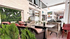 An outdoor seating area with tables and chairs, a vertical garden wall, and a sign for FAJR HOTEL. - Hotel Al Fajr (Oujda)
