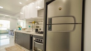 Una cocina moderna con electrodomésticos de acero inoxidable, armarios blancos y un refrigerador grande.