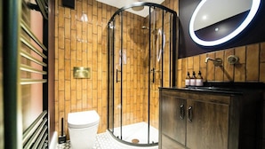 Ein modernes Badezimmer mit Duschkabine, Toilette, Waschtisch mit Spiegel und Pflegeprodukten auf der Ablagefläche.