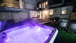 Ein Whirlpool mit violetter Beleuchtung, Treppen zu einer Tür und ein Stuhl in der Nähe des Whirlpools.