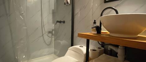 A modern bathroom with a glass-enclosed shower, a toilet, and a sink with a mirror above it.