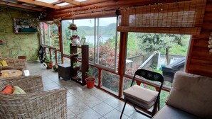 Una habitación acogedora con muebles de mimbre, una mesa de madera y vista a un lago.