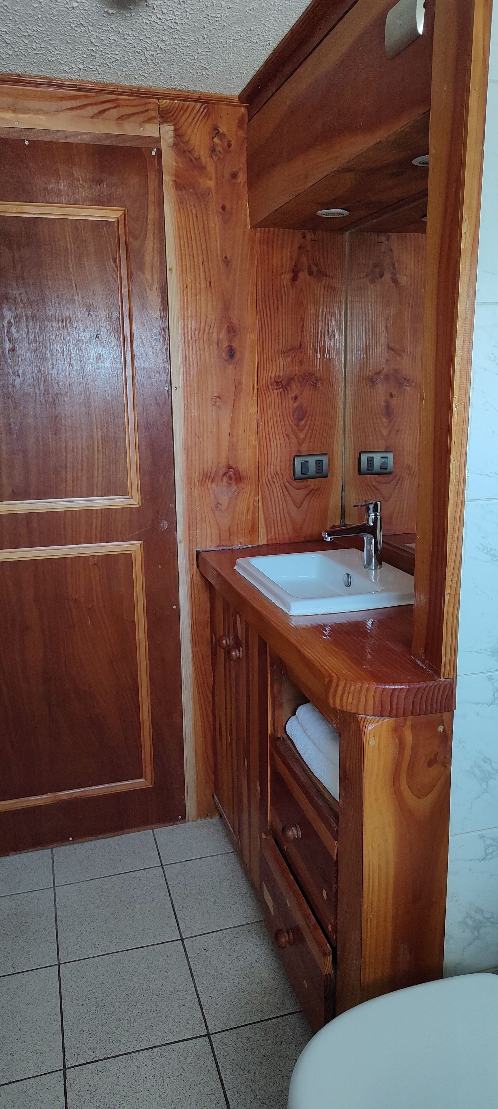 Un baño de madera con lavamanos, espejo y armarios.