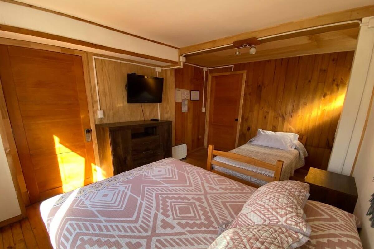Ein Schlafzimmer mit einem Bett, einem Schminktisch, einem Fernseher und Holzwänden.